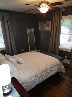A bedroom with a bed, a ceiling fan, a window with curtains, and a wall-mounted mirror. - Charming Modern Home near downtown Atlanta (Atlanta)