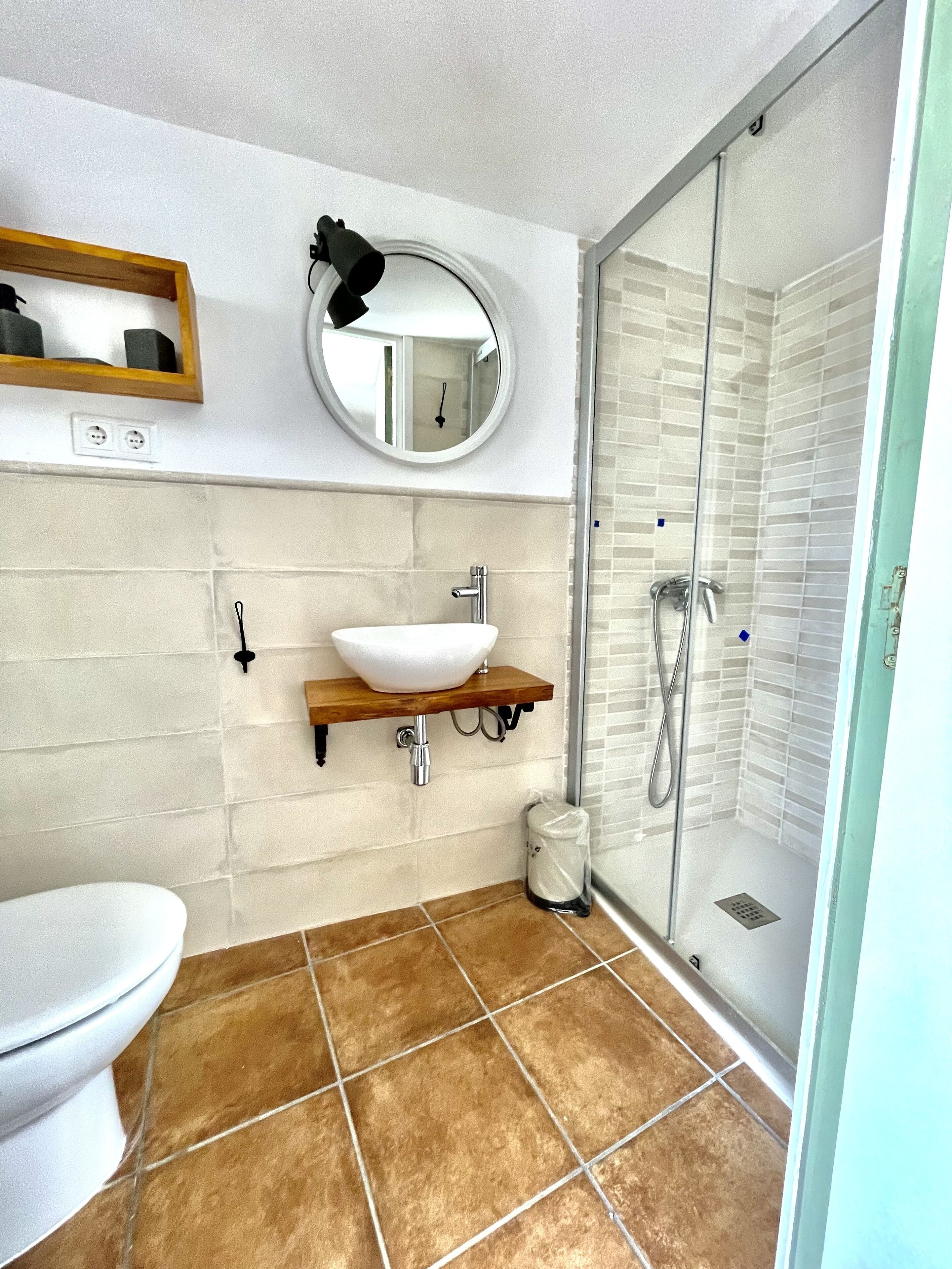 A bathroom with a white sink, mirror, and toilet.