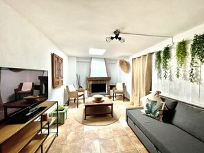 Ein modernes Wohnzimmer mit Flachbildfernseher, Kamin, Sofa und Esstisch.