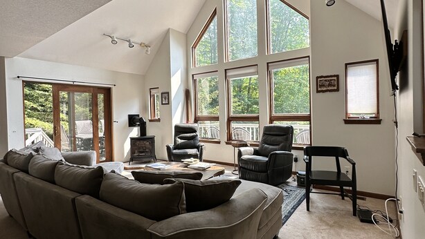 Un salon spacieux avec un haut plafond, de grandes fenêtres, un canapé d’angle et une cheminée.