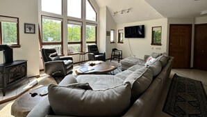 Un salon spacieux avec un grand canapé d’angle, une cheminée et un téléviseur fixé au mur.