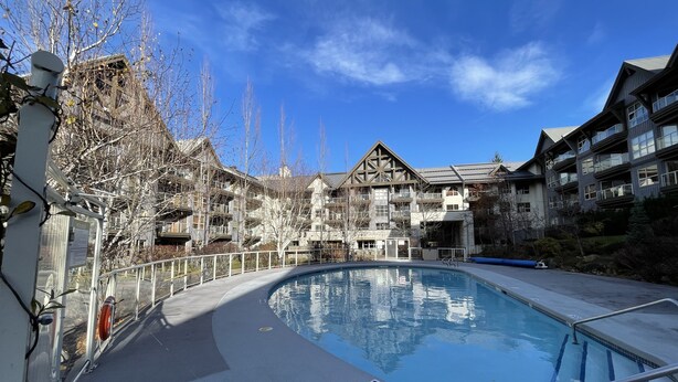 A pool area with a clear blue sky, surrounded by multi-story buildings with balconies and a mix of architectural styles. - Best ski in ski out Condo at Whistler (whistler)