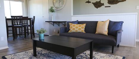 A living room with a dark sofa, a coffee table, and a patterned rug.