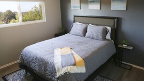 A bedroom with a large bed, a window, and three wall-mounted paintings. - Over the Oaks - Great View - Whole Home - Stylish  (Thousand Oaks)