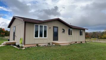 Une maison de plain-pied avec un toit à pignon, de grandes fenêtres et une antenne parabolique sur le toit.