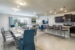 Una cocina moderna con gabinetes oscuros, electrodomésticos de acero inoxidable e iluminación colgante.