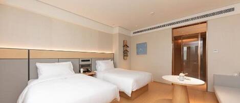 A hotel room with two beds, a small table, and a sofa.