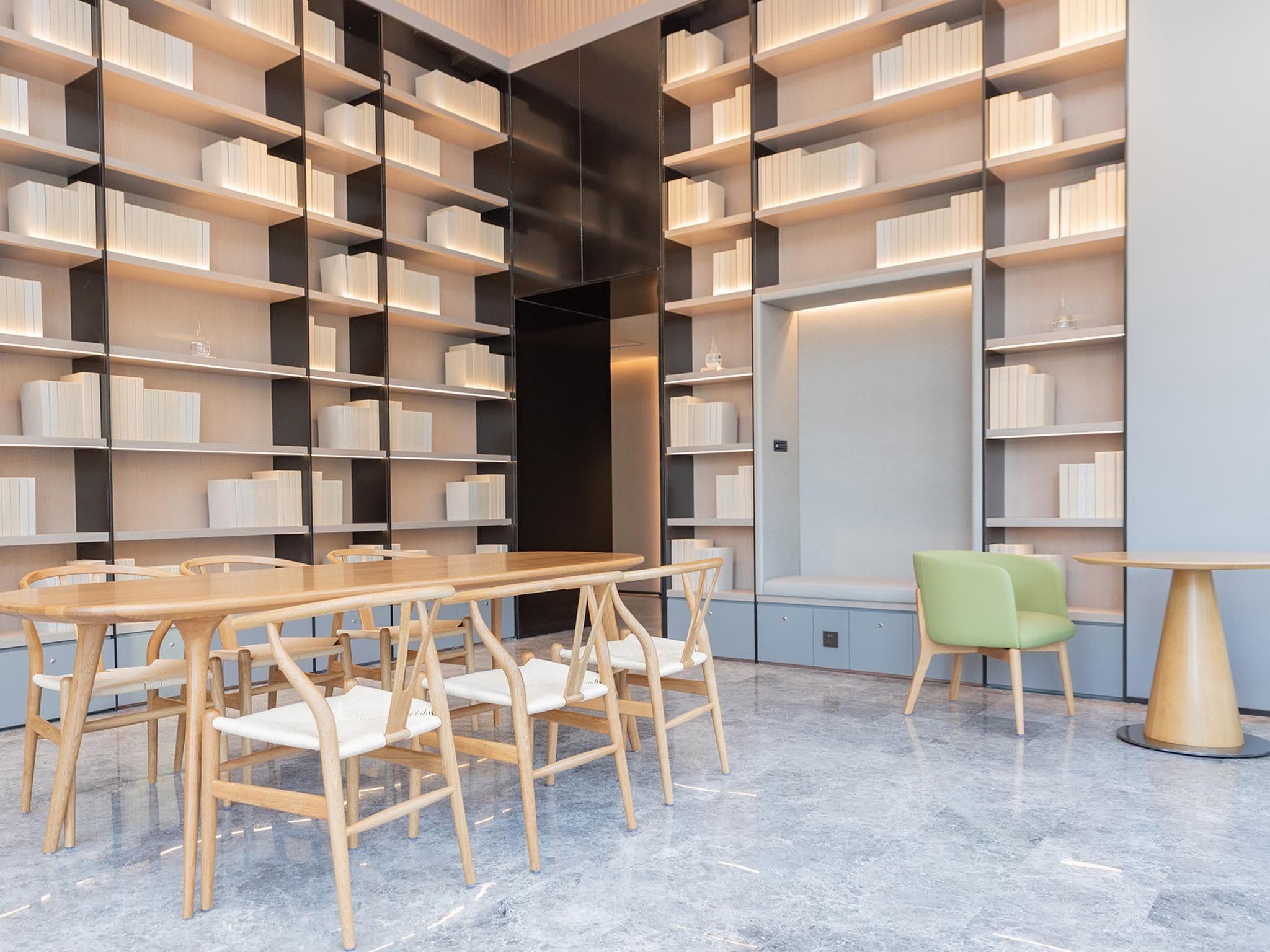 A modern library with bookshelves, a wooden table, and chairs.