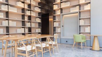 A modern library with bookshelves, a wooden table, and chairs.
