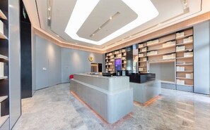 A modern interior with a central reception desk, a large bookshelf, and a clean, minimalist design.