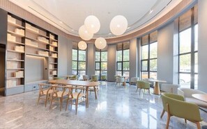 A modern library with a curved ceiling, large windows, and a central table with chairs.