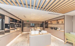 A modern kitchen area with a central island, glass display cases, and a ceiling with wooden slats.