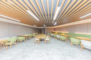 A modern interior with a long table and chairs, a high ceiling with wooden slats, and a neutral color scheme.