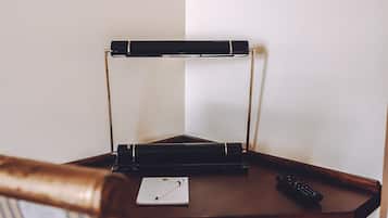 Un bureau en bois avec un ordinateur portable, une télécommande et un cadre représentant une loutre accroché au mur.
