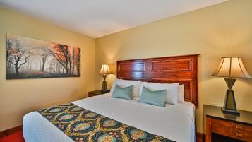 Une chambre d’hôtel avec un grand lit, une tête de lit en bois, deux tables de chevet avec des lampes et un tableau au mur.