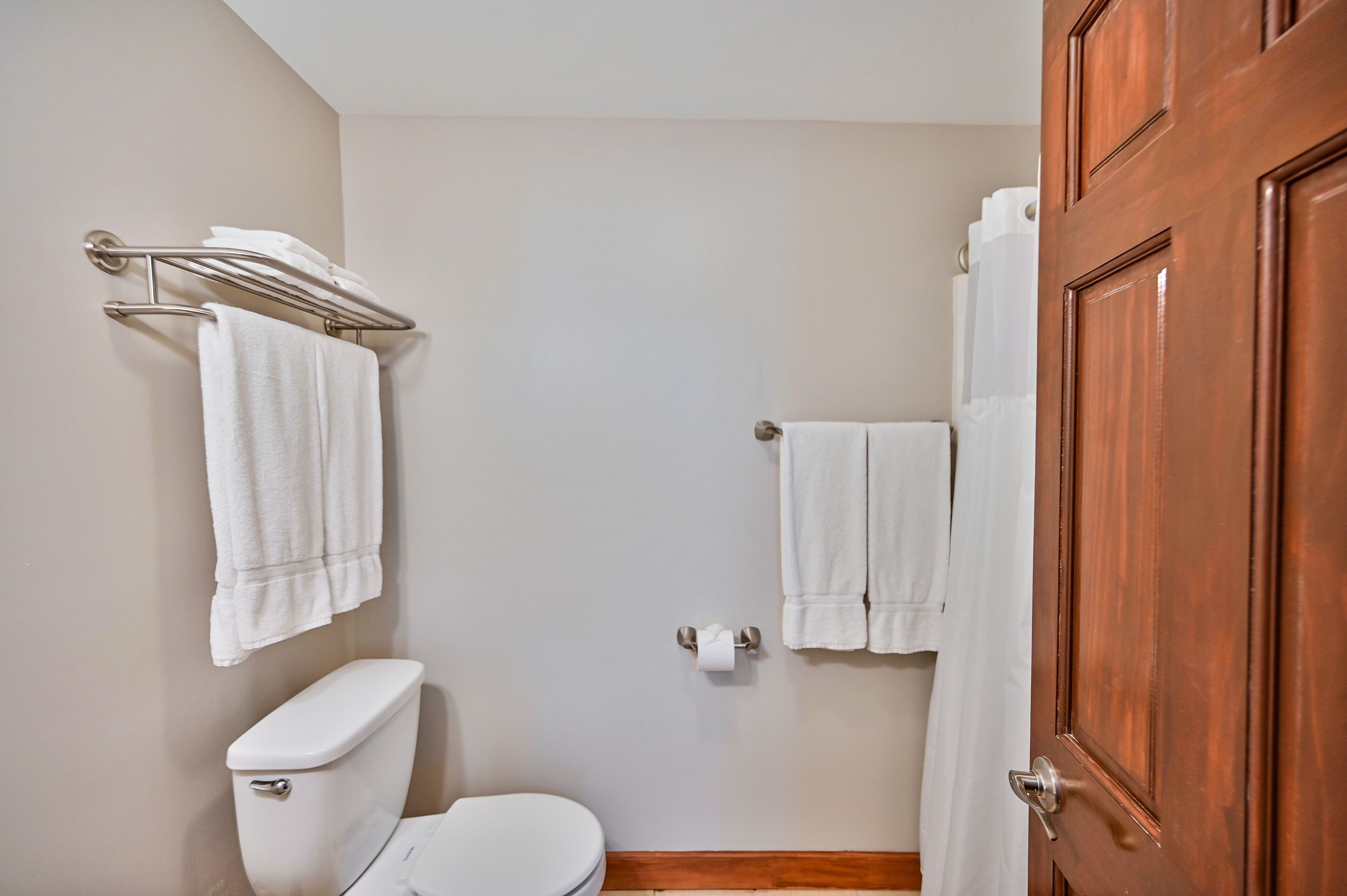 A bathroom with a toilet, a towel rack, and a shower curtain.