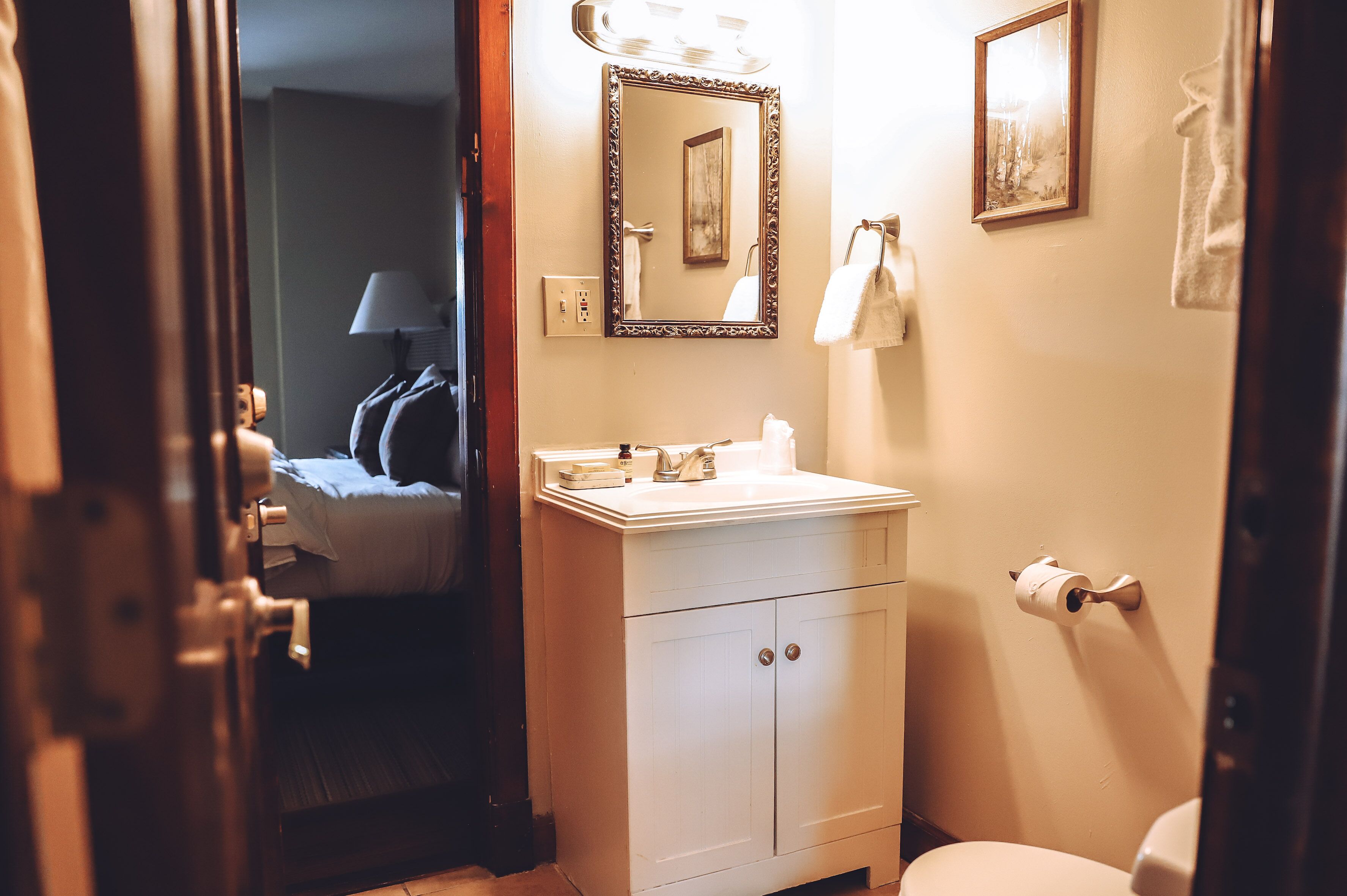 Un baño con lavamanos, espejo y retrete blancos.