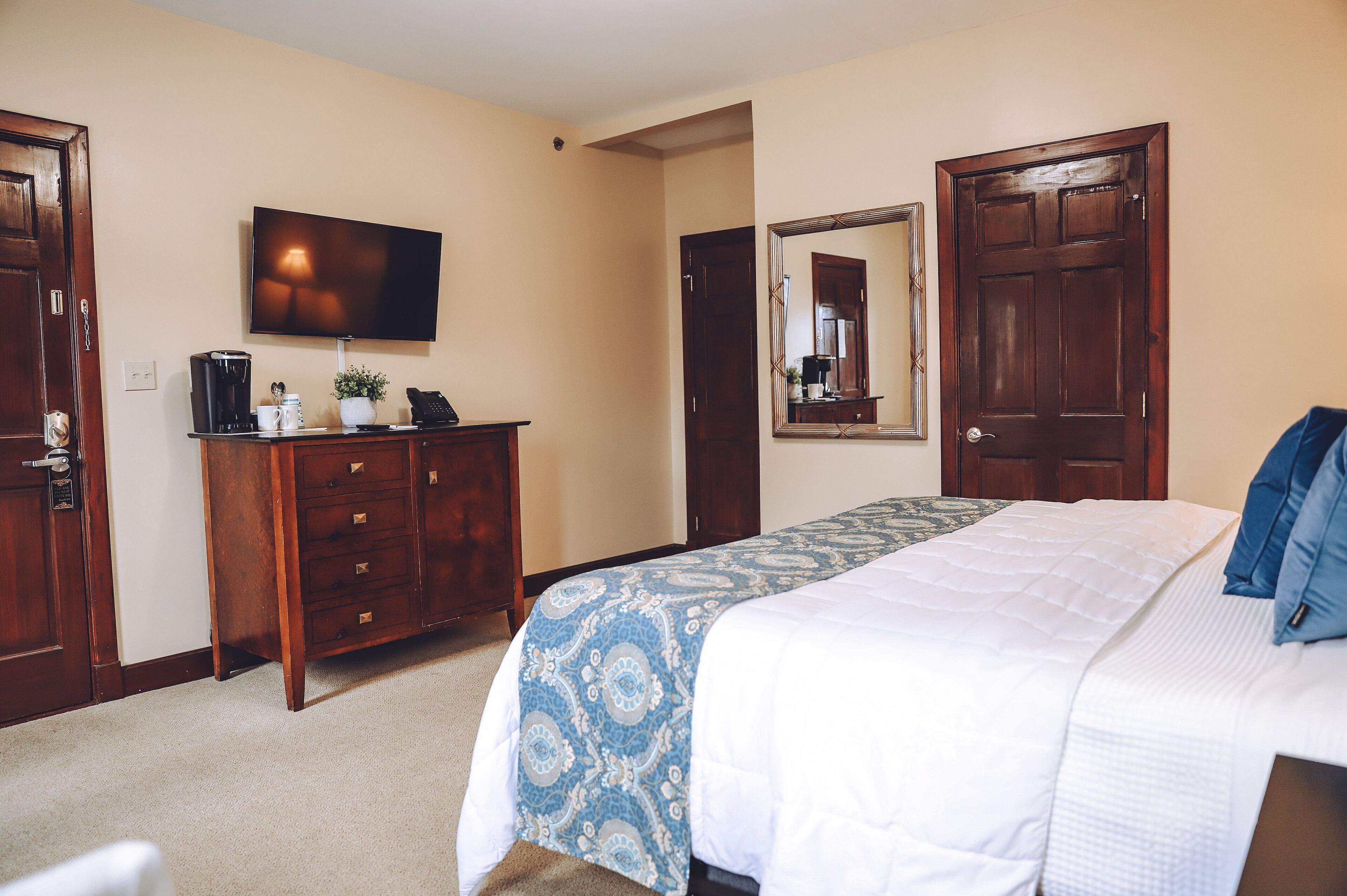 A bedroom with a bed, a dresser, a television, and a mirror.