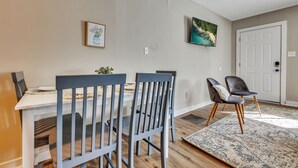 A dining area with a white table and blue chairs, a rug, and two framed pictures on the wall. - Adorable 1BR Unit Near ATL Airport (Atlanta)