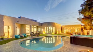 Ein modernes Haus mit Swimmingpool, Sitzgelegenheiten im Freien und Lichterketten.