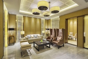 A spacious lobby with a high ceiling, a seating area with a sofa and armchairs, a coffee table, and a dining area with a table and chairs. - Leida Hotel (Dongtai)
