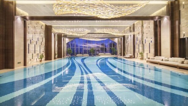 A spacious indoor swimming pool with clear lanes, surrounded by modern furnishings and a contemporary ceiling design. - Leida Hotel (Dongtai)