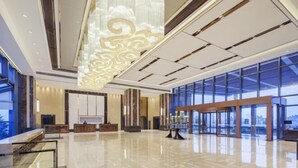 A spacious lobby with a high ceiling, large windows, and a central chandelier. - Leida Hotel (Dongtai)