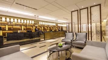 A modern hotel lobby with a reception desk, seating area, and decorative panels.