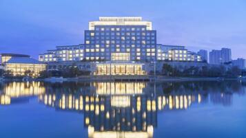 A large hotel with multiple floors and a reflection in the water.