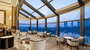 A spacious lounge area with a city view, large windows, and modern furniture. - Leida Hotel (Dongtai)