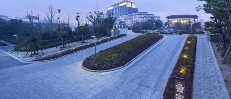 A paved pathway with a landscaped garden and a building in the background.