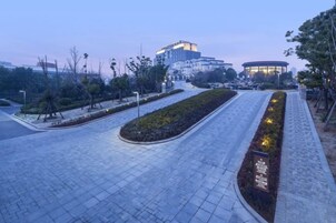 Un sendero pavimentado con un jardín ajardinado y un edificio al fondo.