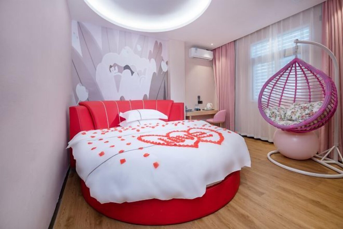 A modern bedroom with a red bed, a hanging chair, and a wall art piece.