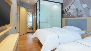 Une chambre d’hôtel avec un lit, une télévision, une porte vitrée donnant sur la salle de bain et une fresque murale.