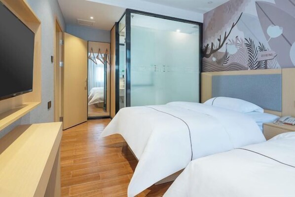 Une chambre d’hôtel avec un lit, une télévision, une porte vitrée donnant sur la salle de bain et une fresque murale.