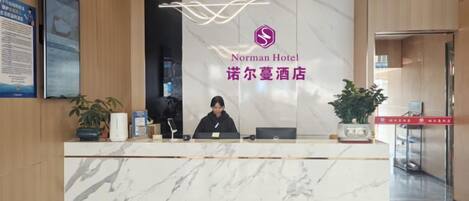 A hotel reception desk with a marble counter, a receptionist, and a logo above the counter.