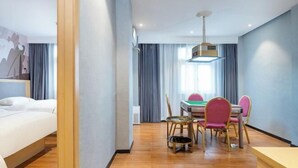 Une chambre d’hôtel avec un lit, une table à manger avec des chaises et un luminaire au plafond.