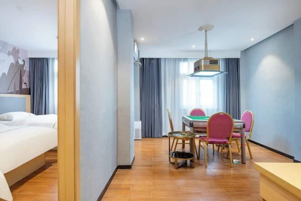 Une chambre d’hôtel avec un lit, une table à manger avec des chaises et un luminaire au plafond.
