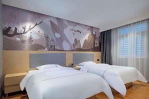 Une chambre d’hôtel avec deux lits, une grande fresque murale et une fenêtre avec des rideaux.