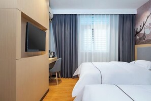 Une chambre d’hôtel avec un lit, un bureau et une chaise, une télévision et une fenêtre avec des rideaux.
