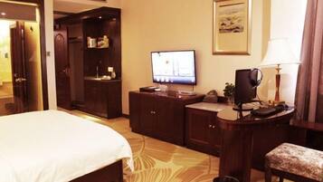 Una habitación de hotel con cama, un escritorio con computadora, televisión y una pequeña zona de estar.