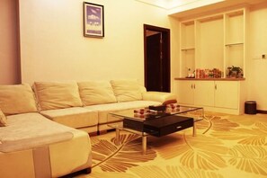 A living room with a sofa, a glass coffee table, and a cabinet with shelves. - Mingdu Boutique Hotel (Hezhou)