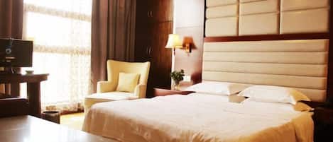 Una habitación de hotel con una cama grande, un escritorio, una silla y un televisor.