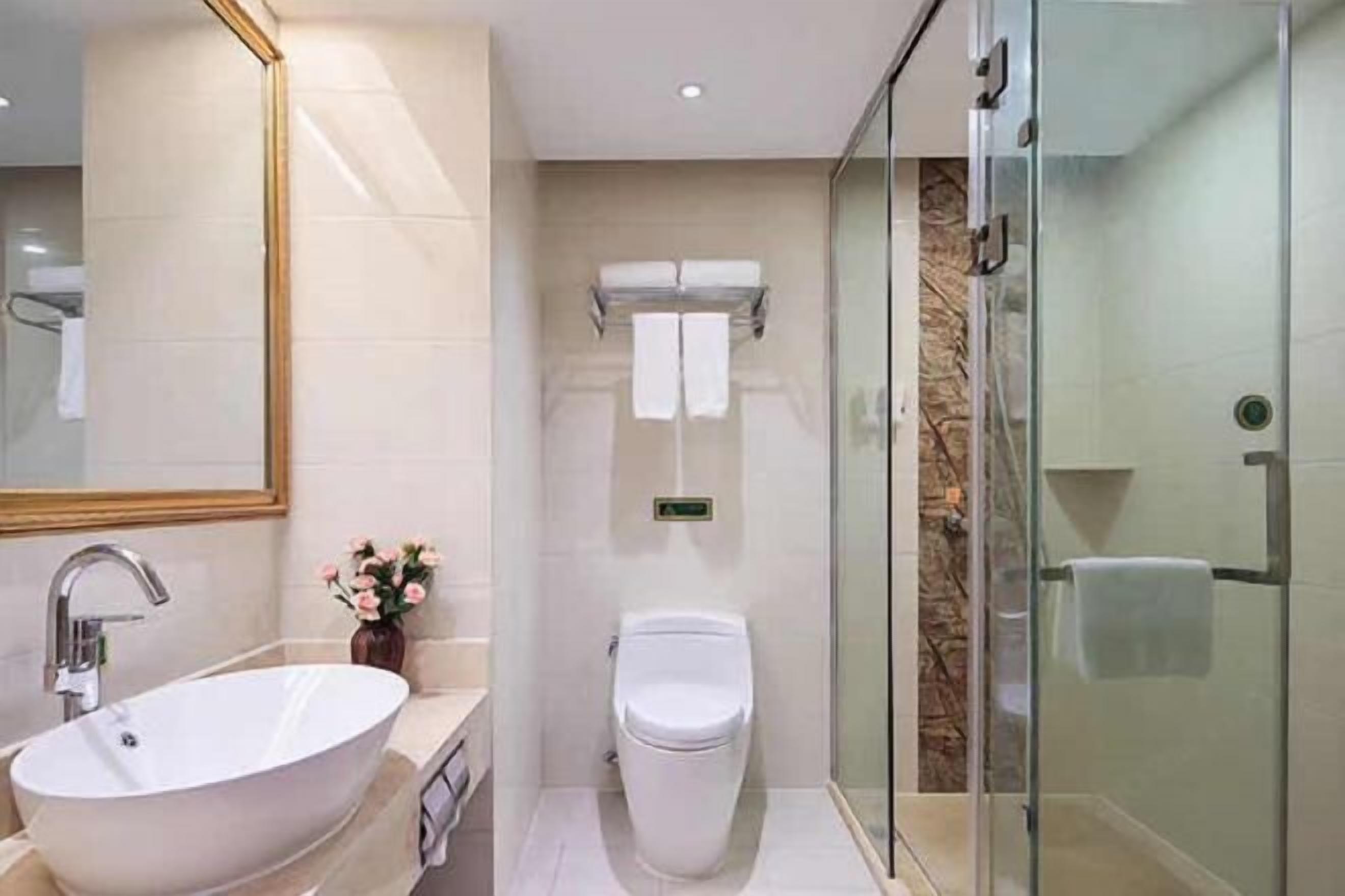 A modern bathroom with a freestanding sink, a toilet, and a glass-enclosed shower.