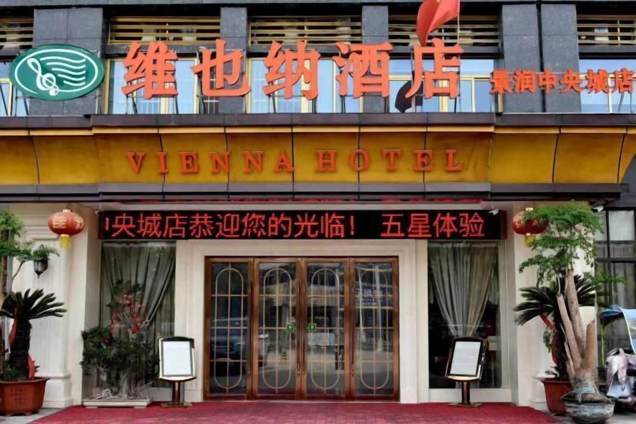 The Vienna Hotel facade with a prominent sign, large glass doors, and potted plants.