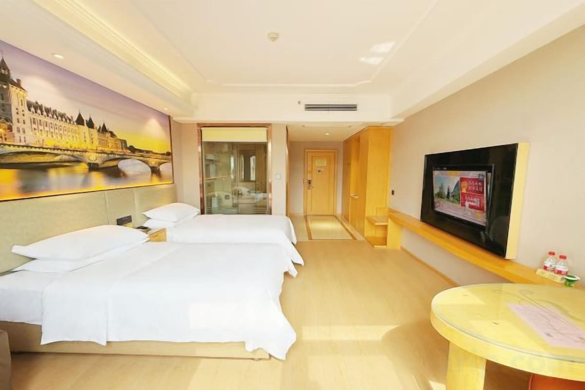 A hotel room with two beds, a television, and a view of a river.