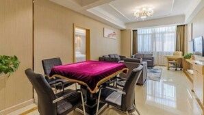 A modern hotel room with a dining area, a sofa, a TV, and a chandelier. - Vienna Hotel (Shou County Jingrun Central City) (Shou County)