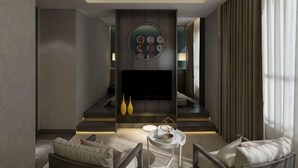 Un salon moderne doté d’un téléviseur à écran plat, d’un mur décoratif de forme arrondie et d’un espace détente avec des canapés et une table basse.