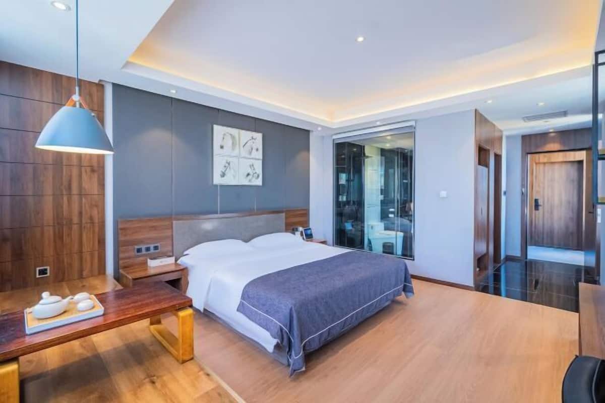 Una habitación de hotel moderna con una cama grande, mesitas de noche, un escritorio y un ventanal amplio.