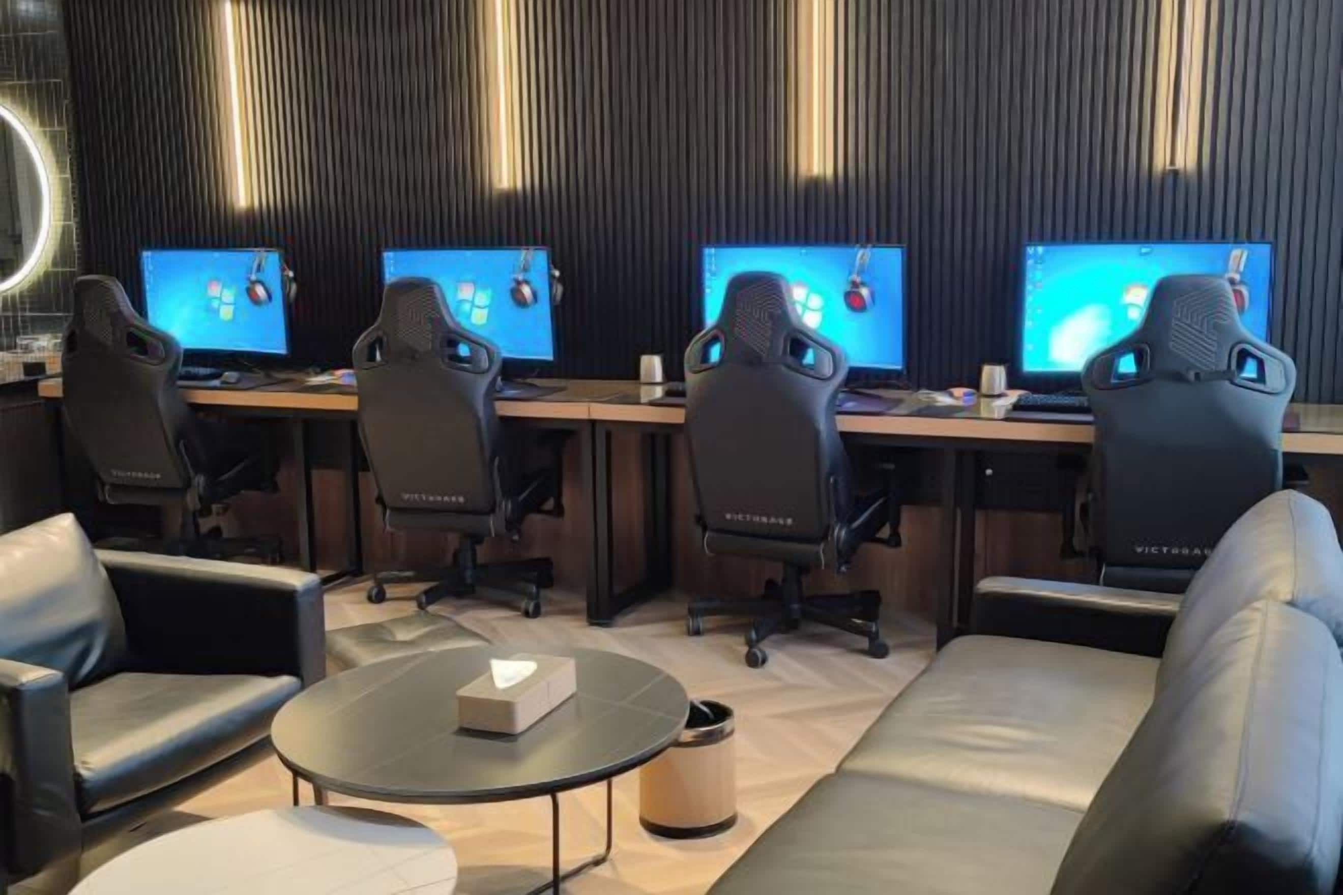 A modern office with four desks, black office chairs, and a round table with a box.